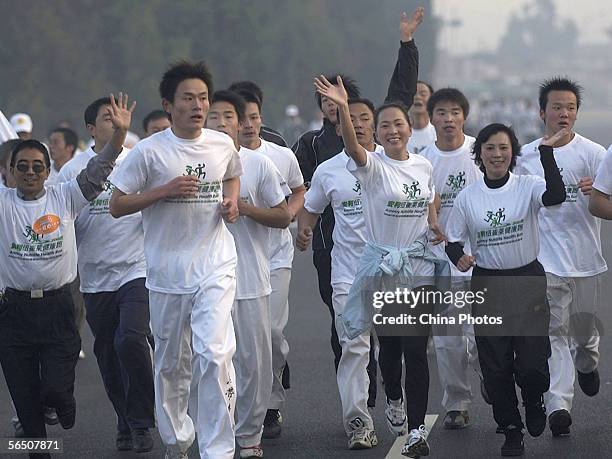 Olympic 5,000 meter champion, Wang Junxia , waves to spectators during a long-distance run to promote health and body building among residents on...