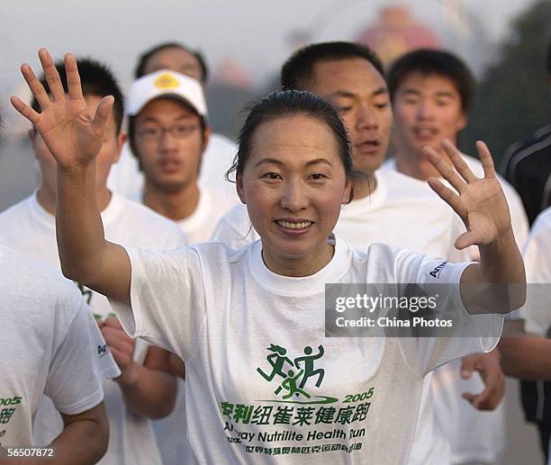 Olympic 5,000 meter champion, Wang Junxia, waves to spectators during a long-distance run to promote health and body building among residents on...