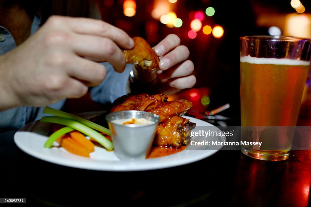 A Man Eating Wings At A Bar