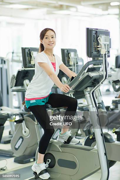 woman riding exercise bike - フィットネスマシン ストックフォトと画像