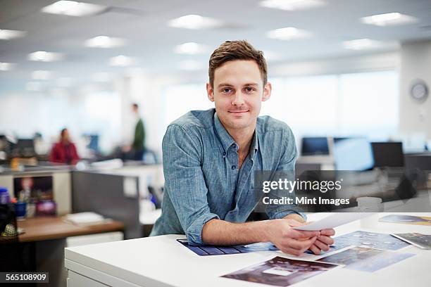 a man smiling and leaning forward on his desk. - industrial portraits character photos et images de collection