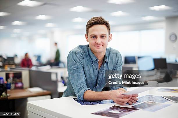 a man smiling and leaning forward on his desk. - editorial office stock pictures, royalty-free photos & images