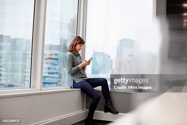 a woman sitting along, using a smart phone. - editorial office stock pictures, royalty-free photos & images