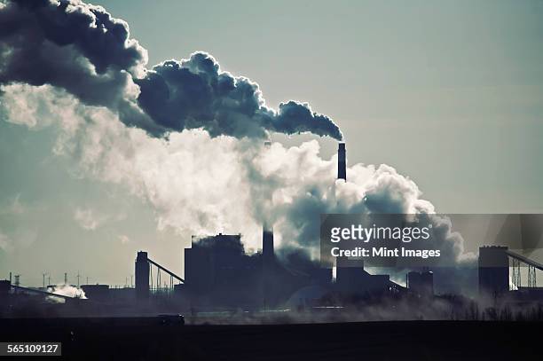heat, steam and smoke rising from the chimneys of a power plant against the sky.  - luftverschmutzung stock-fotos und bilder