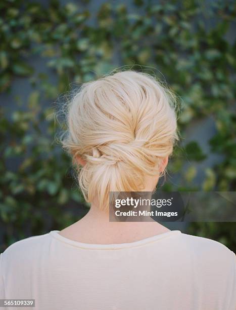 a woman with blonde hair arranged in a knot at the nape of her neck. - nape of neck stock pictures, royalty-free photos & images