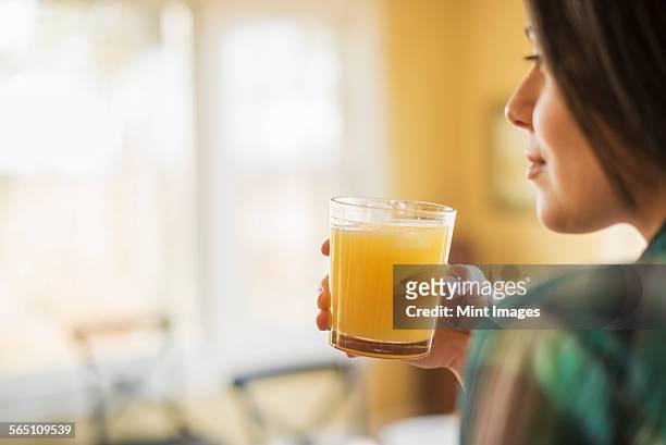 a woman holding a glass of orange juice. - orange juice stock-fotos und bilder