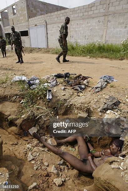 Ivorian soldiers pass by body of an assailant near the Akouedo military camp in Abidjan, 02 January 2006. An armed attack early Monday against a...