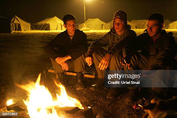 Israeli troops with the 405th artillery battalion keep warm by a fire as they await orders to engage Palestinian targets in nearby the Gaza Strip...