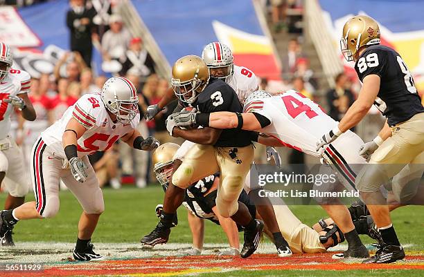 Running back Darius Walker of the Notre Dame Fighting Irish runs as linebakcer A.J. Hawk of the Ohio State Buckeyes grabs him in the first quarter of...