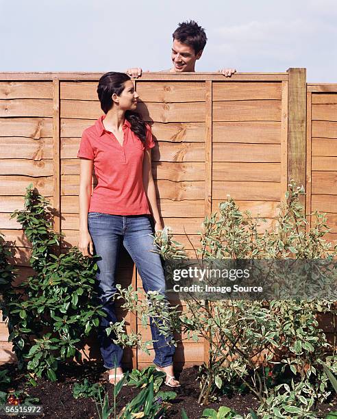 man looking over fence at woman - leaning stockfoto's en -beelden