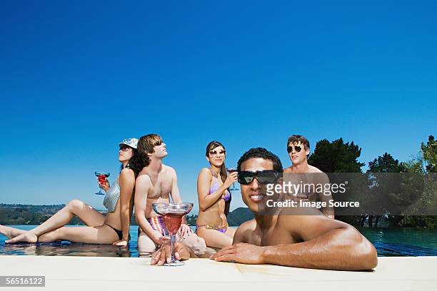 friends drinking cocktails in a swimming pool - poolside glamour stock pictures, royalty-free photos & images