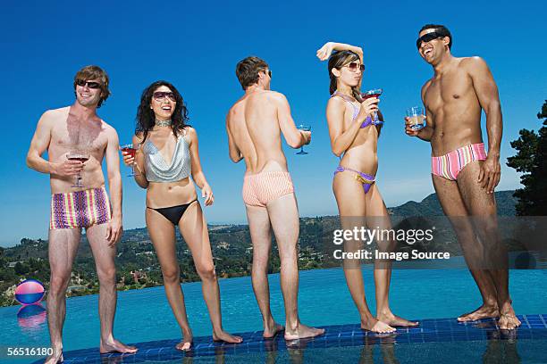 friends drinking cocktails poolside - zwembroek stockfoto's en -beelden