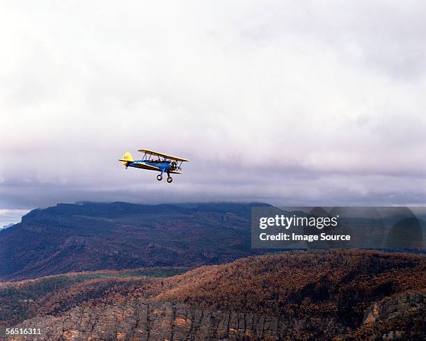 biplane with mountains in the background - biplane stock pictures, royalty-free photos & images