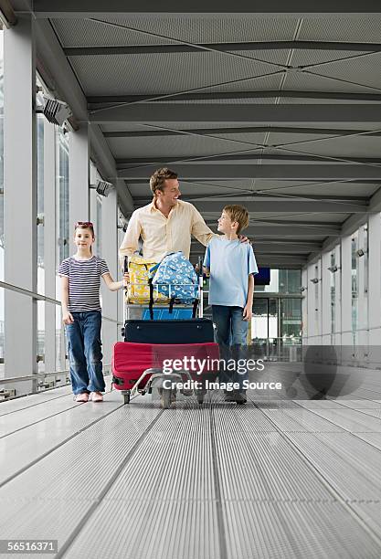 father with children in airport - luggage trolley stockfoto's en -beelden