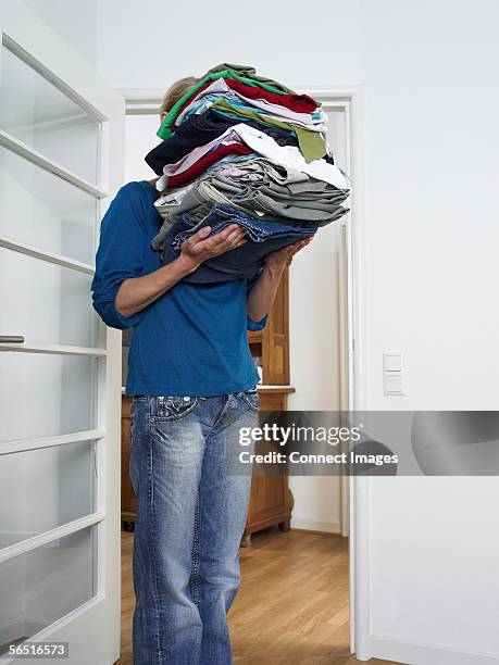 woman carrying pile of laundry - tâche fastidieuse photos et images de collection