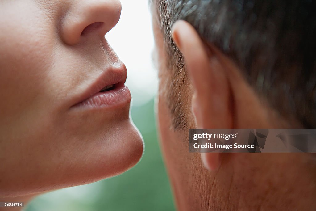 Woman whispering into man's ear