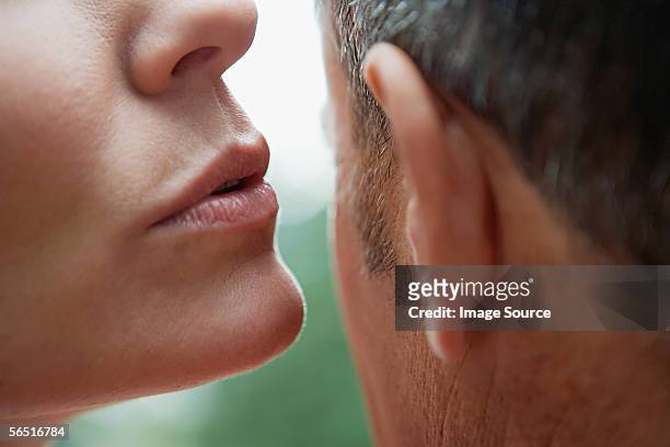 woman whispering into man's ear - ear bildbanksfoton och bilder