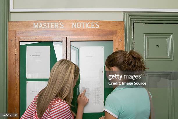 girls reading a noticeboard - exam hall stock-fotos und bilder