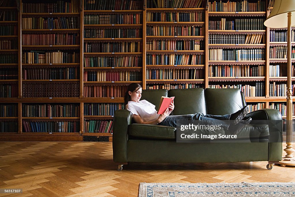 Mädchen Lesen auf einem sofa in der Bibliothek