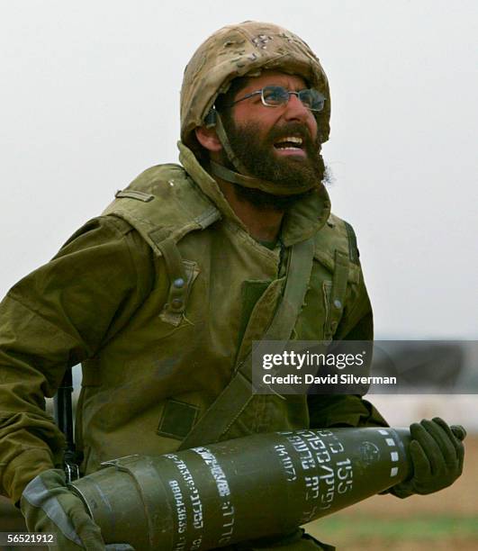 An Israeli soldier carries an artillery shell as his mobile artillery unit is deployed with orders to open fire against Palestinian militants in...