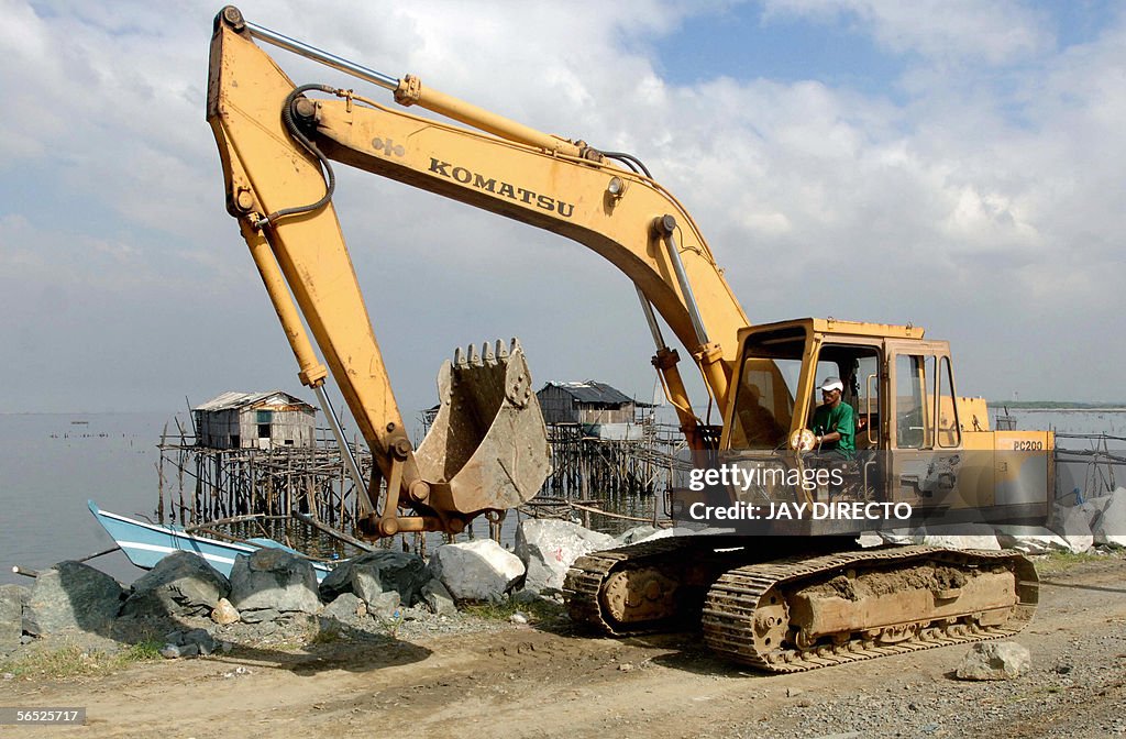 A backhoe piles up boulders for a seawal