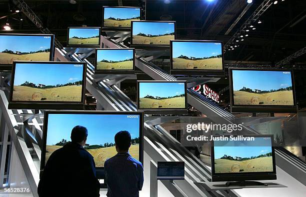 Two attendees look at a display of Aquos flat screen televisions on the opening day of the 2006 Consumer Electronics Show January 5, 2006 in Las...