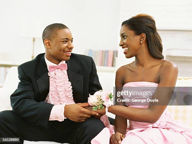 teenage couple sitting on a sofa and holding hands - prom dress stockfoto's en -beelden