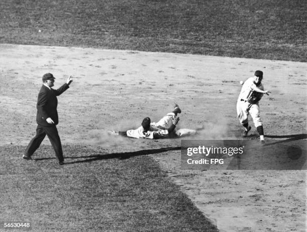 American baseball player Billy Herman of the Chicago Cubs throws the ball to first base to complete a double play in the 7th inning of the third game...