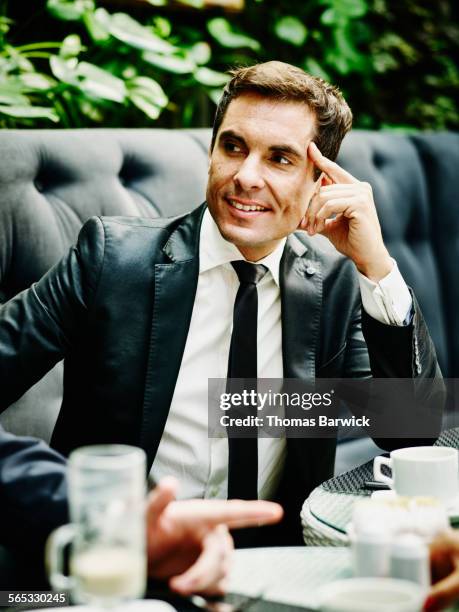 smiling businessman sitting in lunch meeting - true luxury stock-fotos und bilder