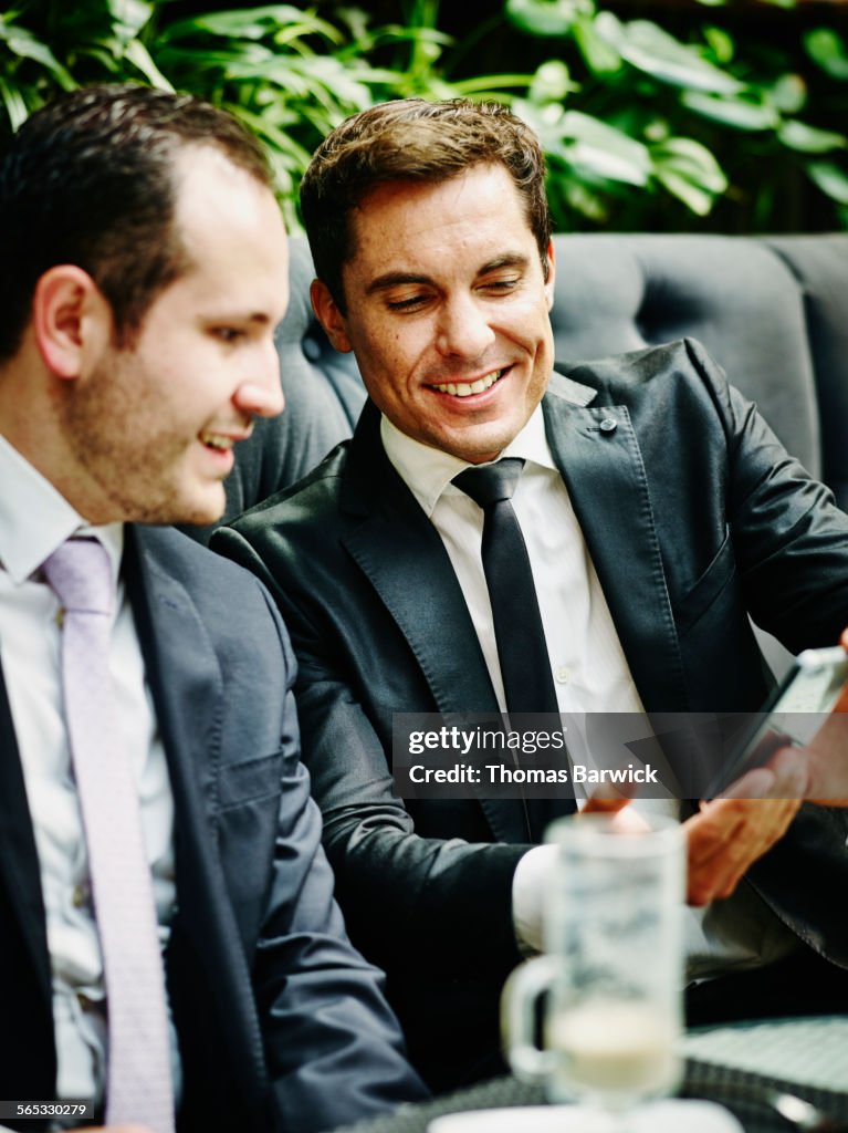 Businessman showing smartphone to colleague