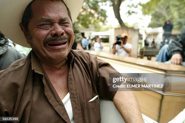 Un familiar de un recluso muerto la vispera llora cuando sale de la morgue con uno de los feretros, en Tegucigalpa el 6 de enero de 2006. Trece...