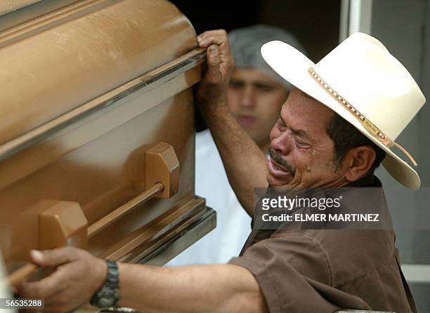 Un familiar de un recluso muerto la vispera llora cuando sale de la morgue con uno de los feretros, en Tegucigalpa el 6 de enero de 2006. Trece...