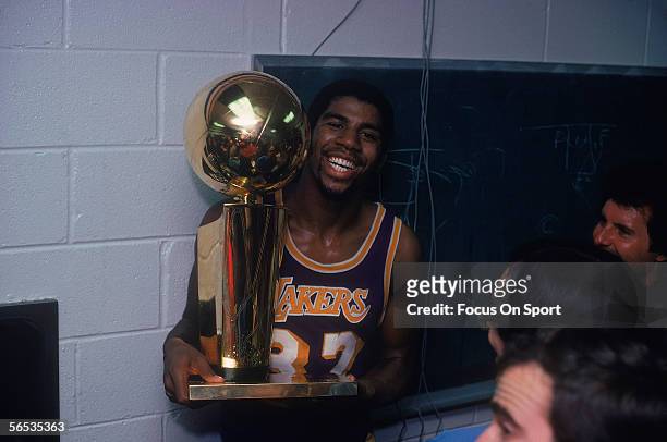 Magic Johnson of the Los Angeles Lakers celebrates with the Walter A. Brown championship trophy after winning Game 6 and series against the...