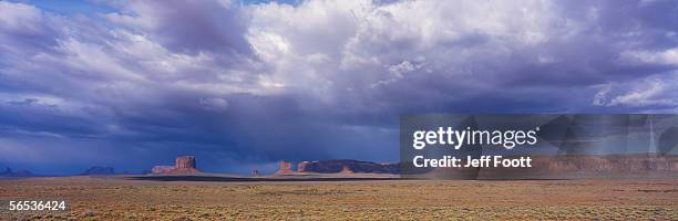 voluminous clouds hover over an expansive valley. monument valley, utah. - monument valley stock-fotos und bilder