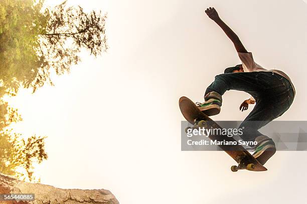 teenage boy performing stunt on skateboard - extreme sports kids stock pictures, royalty-free photos & images