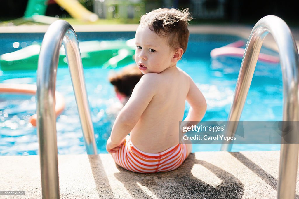 Boy sitting at the edge of the pool
