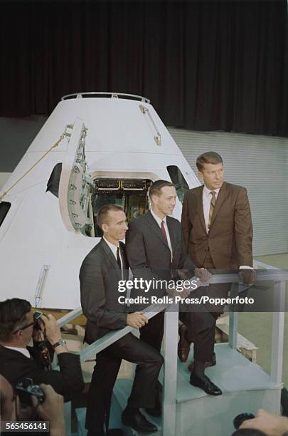United States astronauts and crew of the Apollo 7 spaceflight mission pictured together standing in front of a full size model of a Apollo Command...