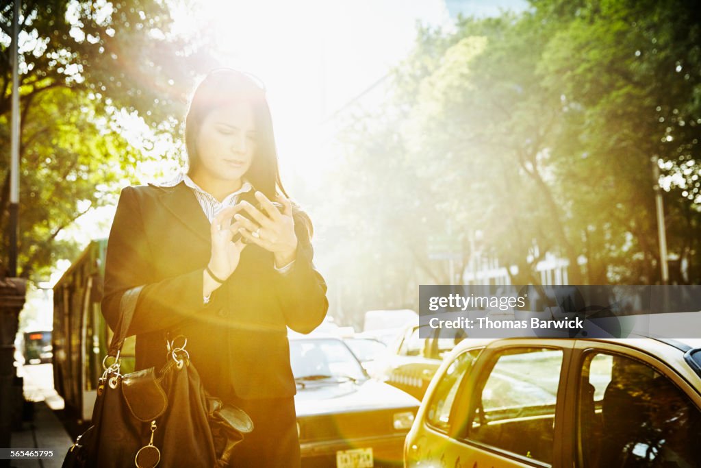 Businesswoman using smartphone waiting for taxi