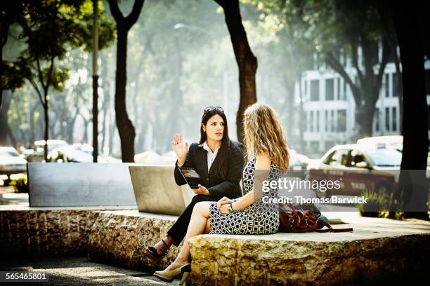 businesswomen discussing project in city park - bank meeting stock-fotos und bilder