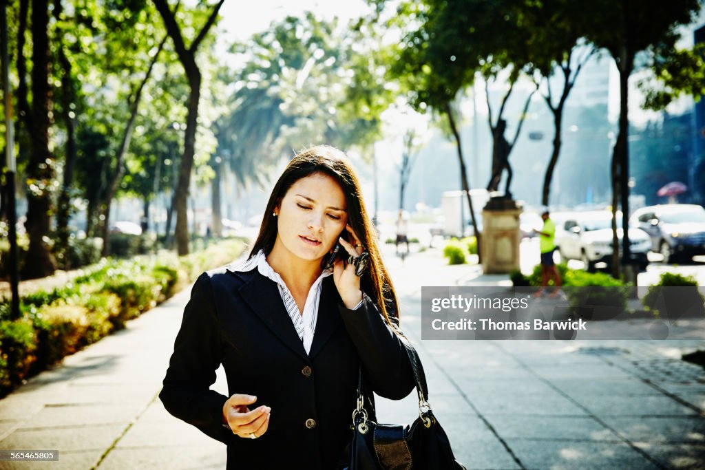 Businesswoman talking on smartphone on sidewalk