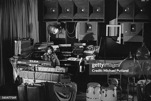 Greek composer of electronic music, Vangelis, surrounded by equipment at a venue, 28th January 1976.