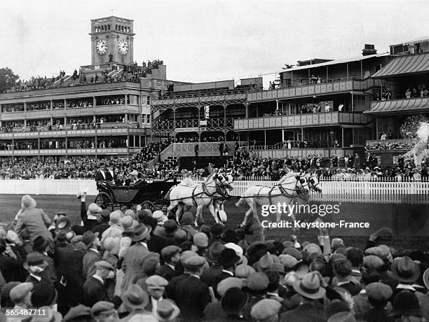 Dans leur calèche tirée par quatre chevaux blancs, le Roi George V et la Reine Mary sont acclamés par les spectateurs venus assister à la course...