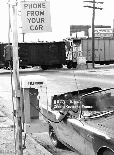 Téléphone à long câble placé sur le bord du trottoir afin que les conducteurs passent leurs appels depuis leur voiture, à La Nouvelle-Orléans,...
