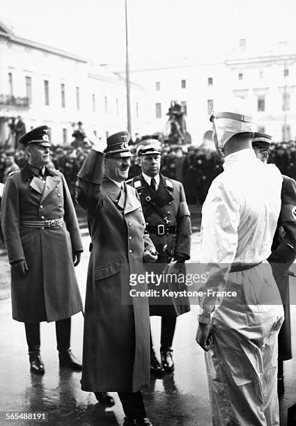 Hitler salue en souriant le coureur britannique Seaman, des écuries Mercedes-Benz, dans la cour de la Chancellerie en compagnie de Wilhelm Keitel et...