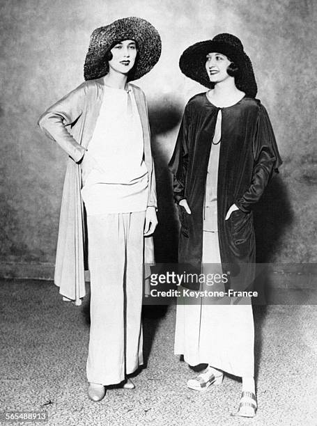 Mannequins présentant deux nouveaux costumes de plage aux robes longues et teintes très vives avec sandales à semelles de bois, circa 1925.