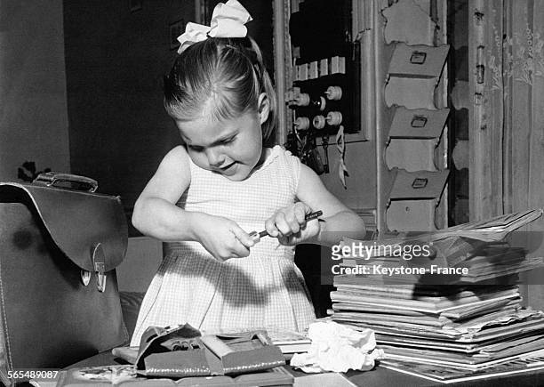 Une petite fille taille ses crayons et range ses affaires dans son cartable en prévision de la rentrée des classes le 13 septembre 1960.