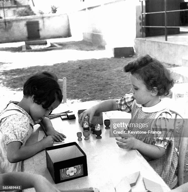 Deux petites filles s'amusent à peindre des oeufs dans le cadre des colonies de vacances du Ministère de l'Intérieur, en août 1944 en France.