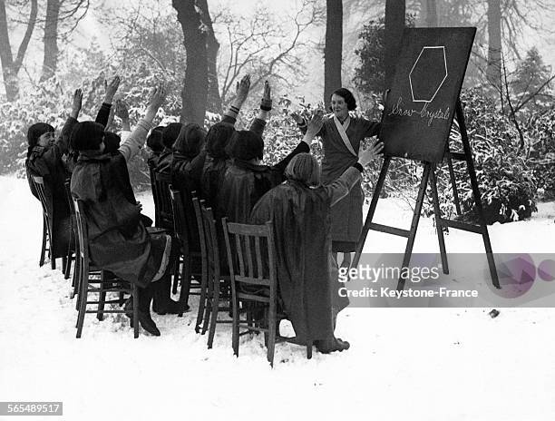 Une institutrice britannique donne un cours sur la structure du flocon de neige à sa classe en plein air, sous la neige le 23 février 1935 à...