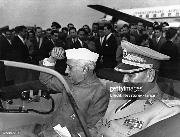 Assis à l'arrière de la voiture, le Président de la République fédérative socialiste de Yougoslavie, Josip Broz Tito lit des notes alors que le...