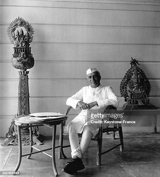 Le Premier ministre de l'Inde Jawaharlal Nehru assis sur la terrasse couverte de sa maison, devant des statues hindoues et aspidistras, à New Delhi,...